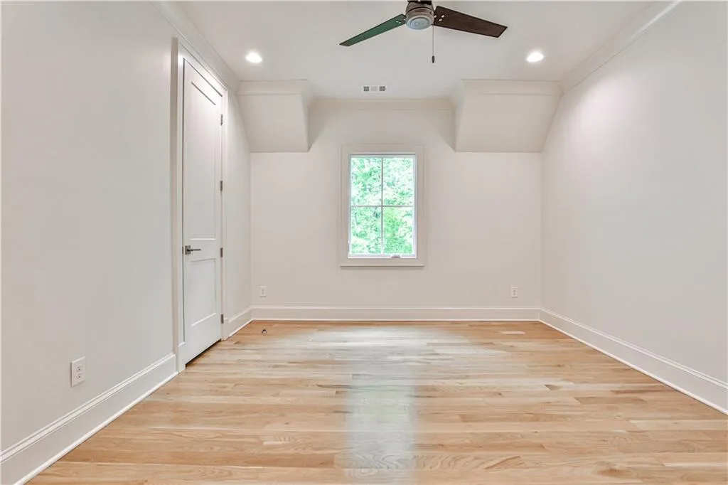 Empty room with crown molding, ceiling fan, and light wood-type flooring