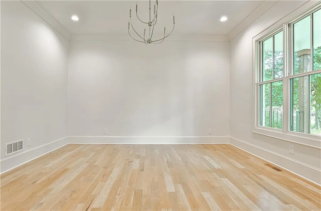 Front room off entry hallway featuring crown molding, light wood-type flooring, and a chandelier