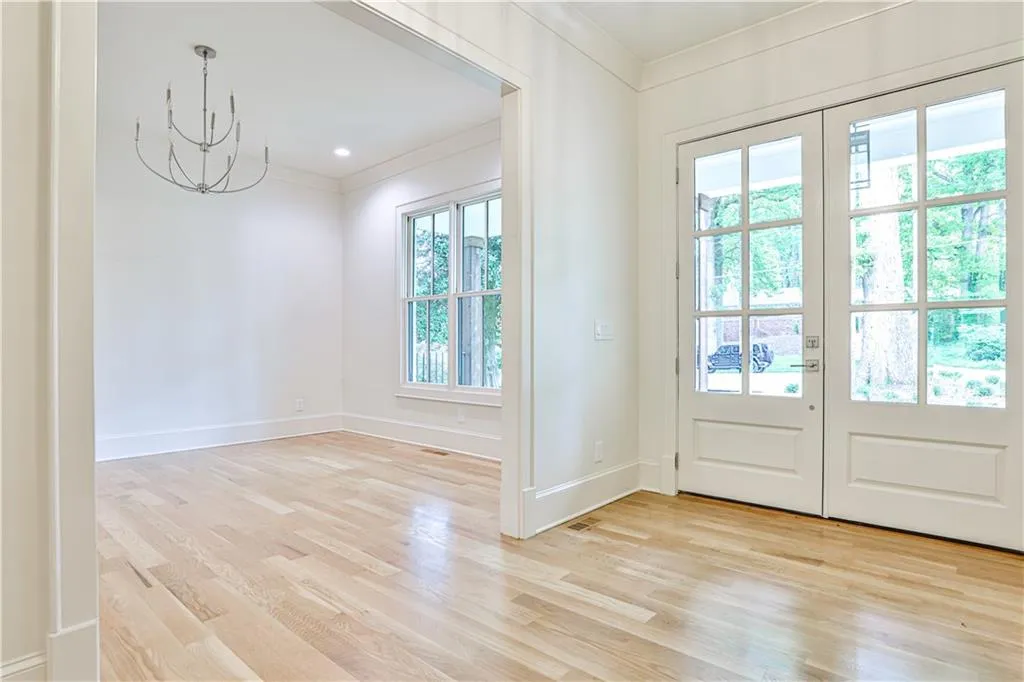 Doorway with french doors, plenty of natural light, light hardwood / wood-style floors, and crown molding