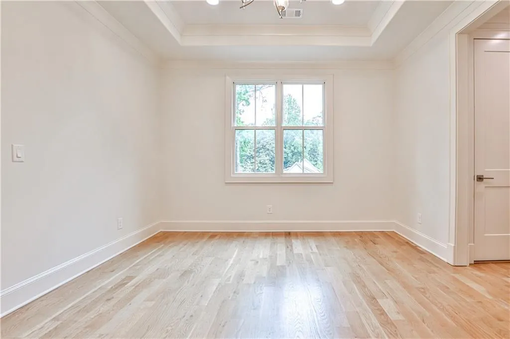 Unfurnished room featuring ornamental molding, light hardwood / wood-style floors, and a raised ceiling