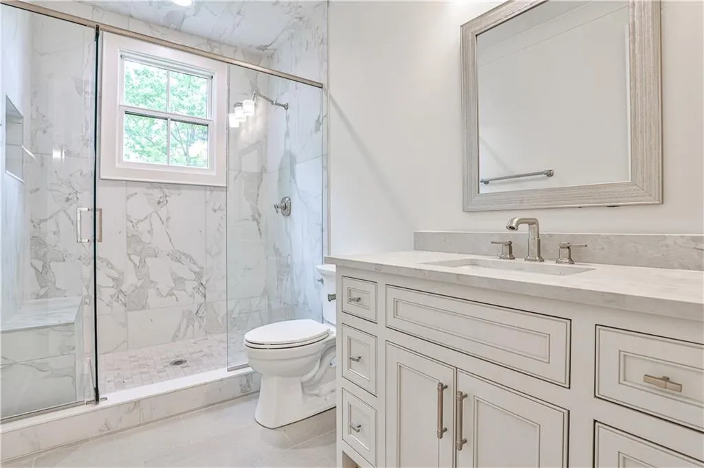Bathroom with a shower with door, vanity, toilet, and tile flooring