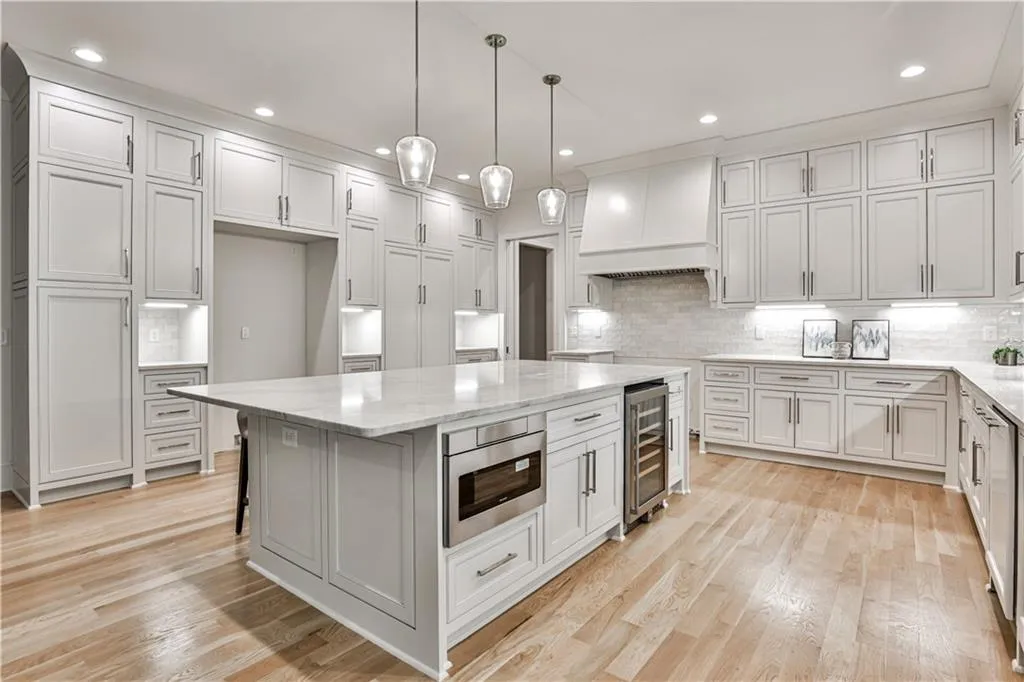Kitchen with light hardwood / wood-style flooring, tasteful backsplash, a center island, and custom exhaust hood