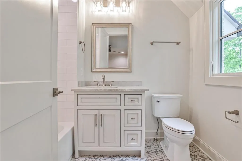 Bathroom with tile flooring, lofted ceiling, vanity, and toilet