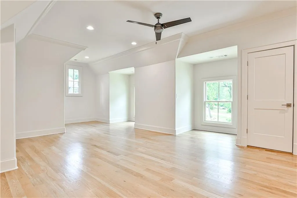 Spare room featuring lofted ceiling, ceiling fan, and light wood-type flooring