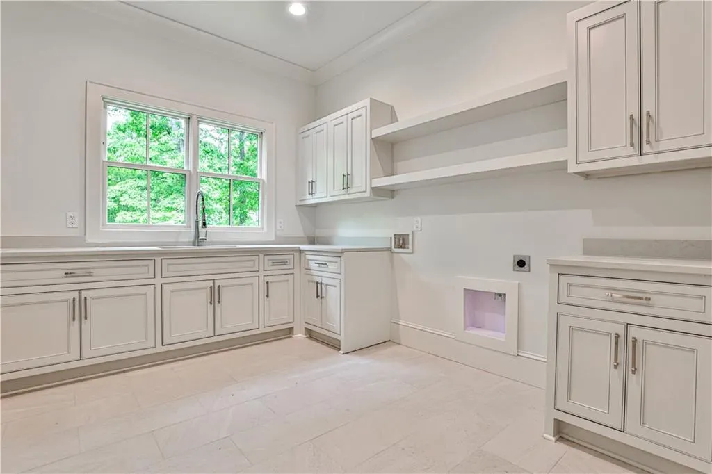 Laundry area on main level next to mud room featuring light tile floors, cabinets, sink, hookup for a washing machine, and electric dryer hookup
