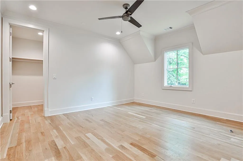 Additional living space featuring vaulted ceiling, ceiling fan, and light wood-type flooring