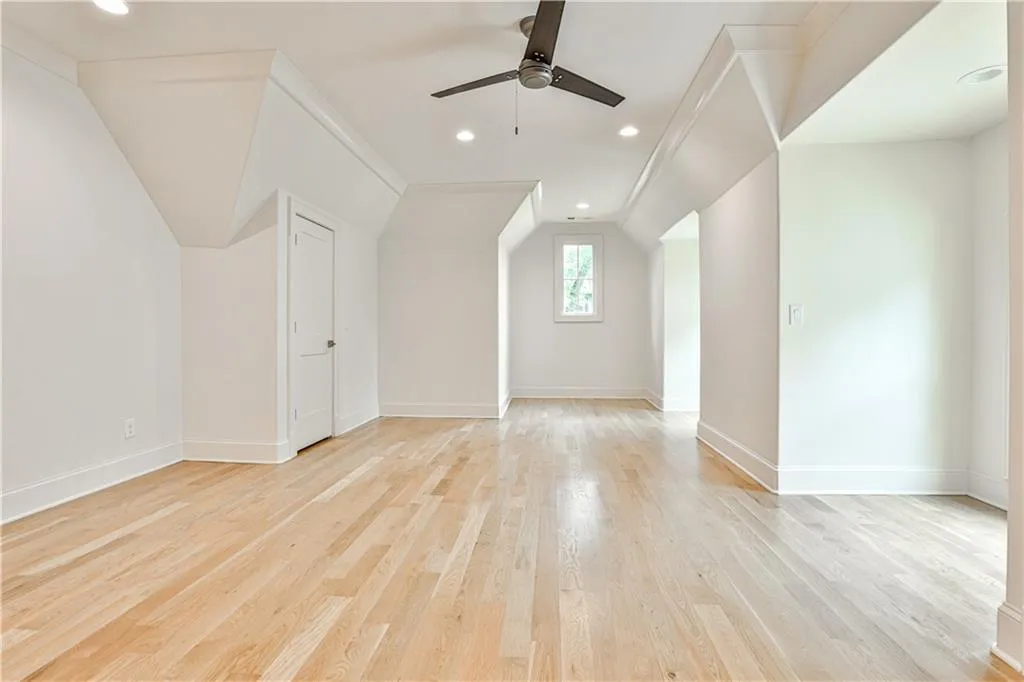 Bonus room with lofted ceiling, ceiling fan, and light wood-type flooring