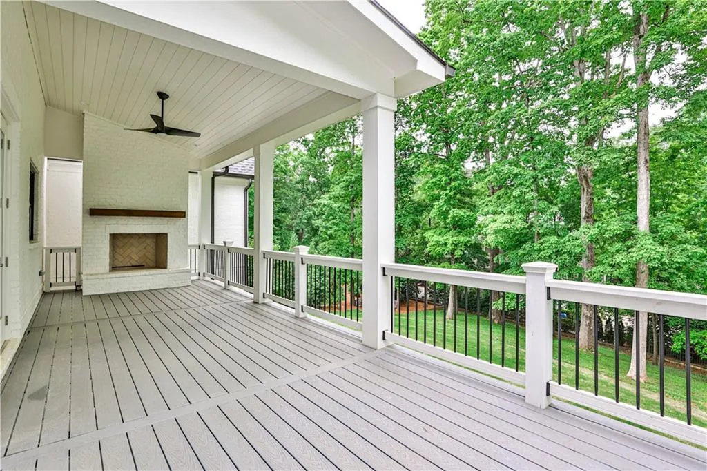 Wooden deck featuring ceiling fan, a yard, and an outdoor brick fireplace