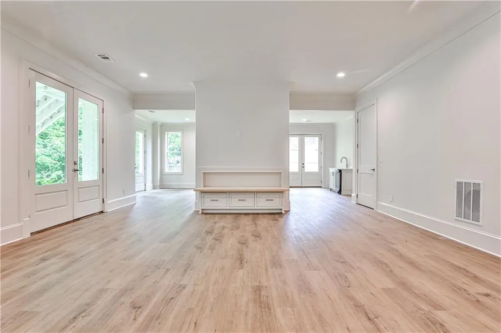 Basement with french doors, crown molding, light wood-type flooring, and plenty of natural light