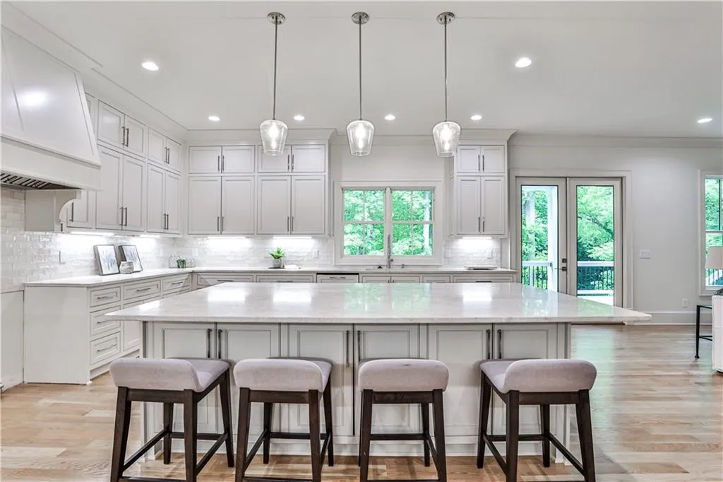Kitchen with a center island, premium range hood, hanging light fixtures, backsplash, and a wealth of natural light