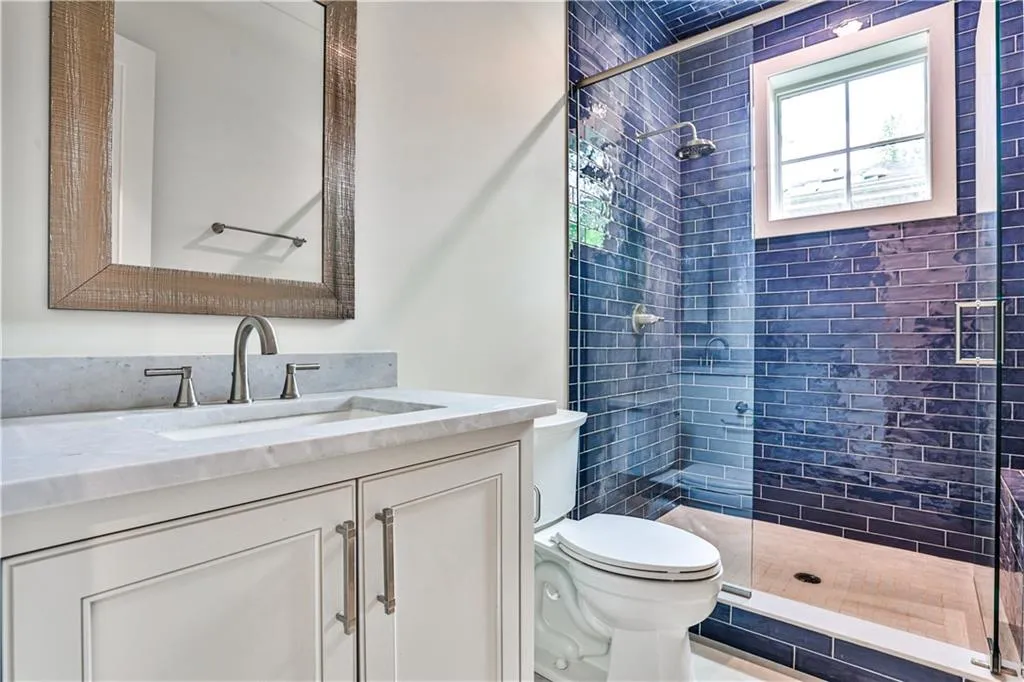 Bathroom with toilet, vanity, and a tile shower
