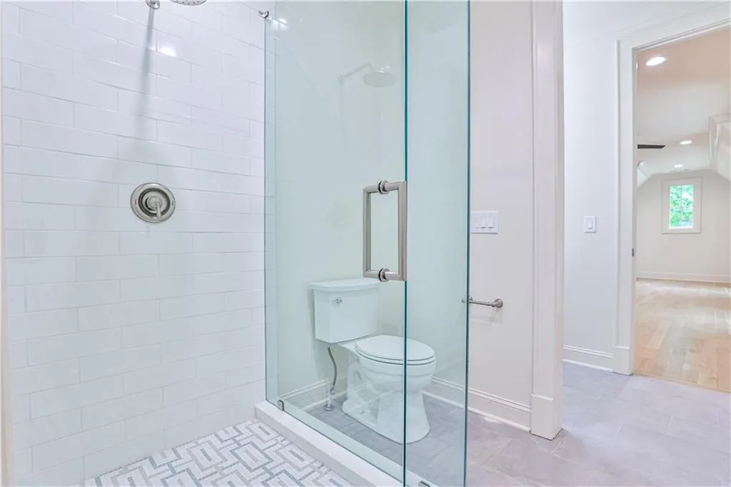 Bathroom with a shower with door, toilet, and tile floors