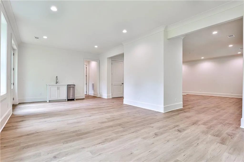 Unfurnished basement room with light hardwood / wood-style flooring and ornamental molding