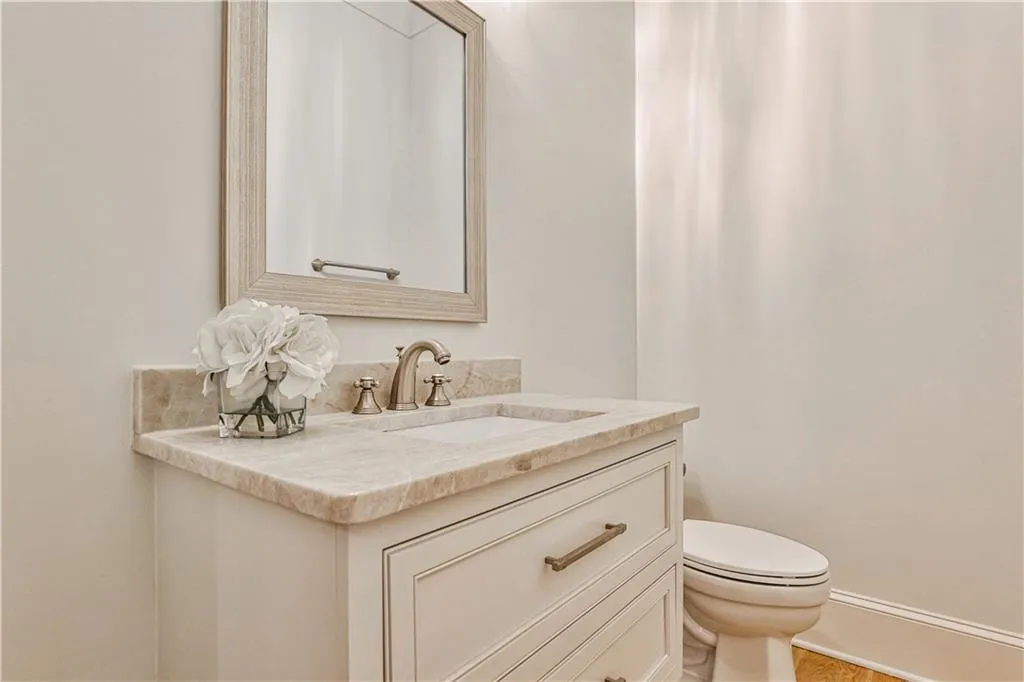 Half Bathroom on main level featuring wood-type flooring, vanity, and toilet
