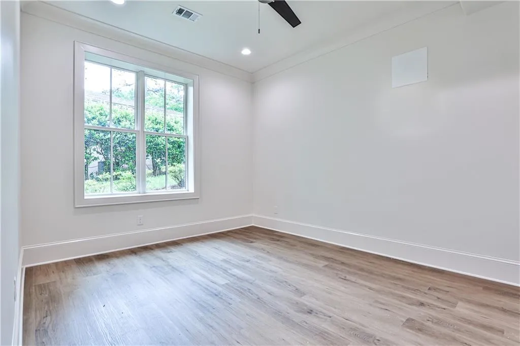Spare room featuring a healthy amount of sunlight, ceiling fan, and light hardwood / wood-style floors