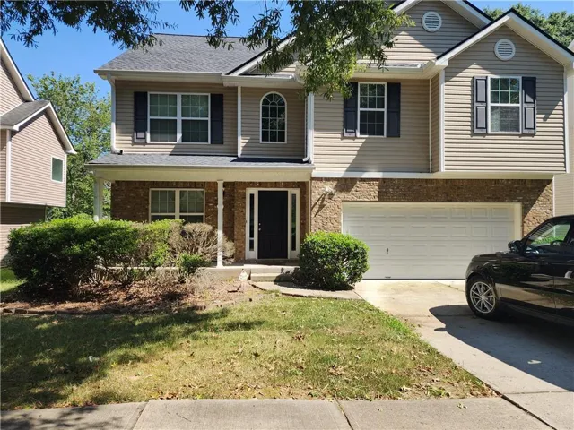 Two-story residence featuring a brick and siding exterior, arched window, and a two-car garage