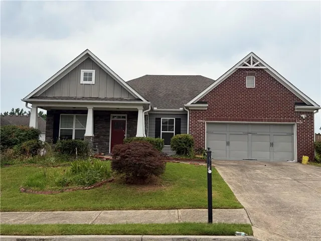 Brick and siding exterior featuring a covered front porch with stone accents and columns