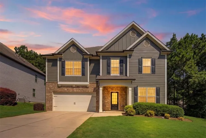 Two-story Colonial-style home featuring a brick and fiber cement board exterior with multiple gabled rooflines and circular attic vents