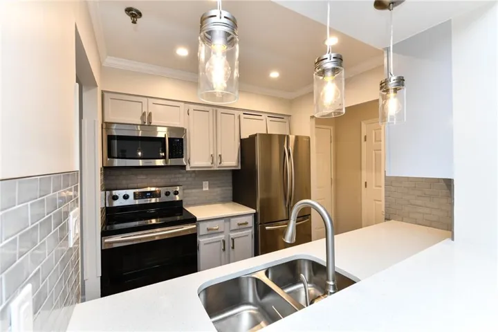 Kitchen featuring light-toned cabinetry, stainless steel appliances, and a double basin sink with a gooseneck faucet