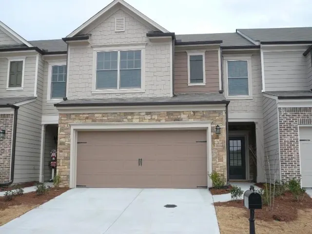 Multi-story residential facade featuring a prominent two-car garage with a brown door and decorative hardware
