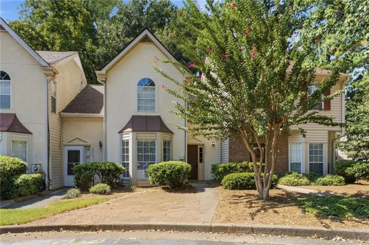 Two-story facade with arched window, bay window, and mature landscaping