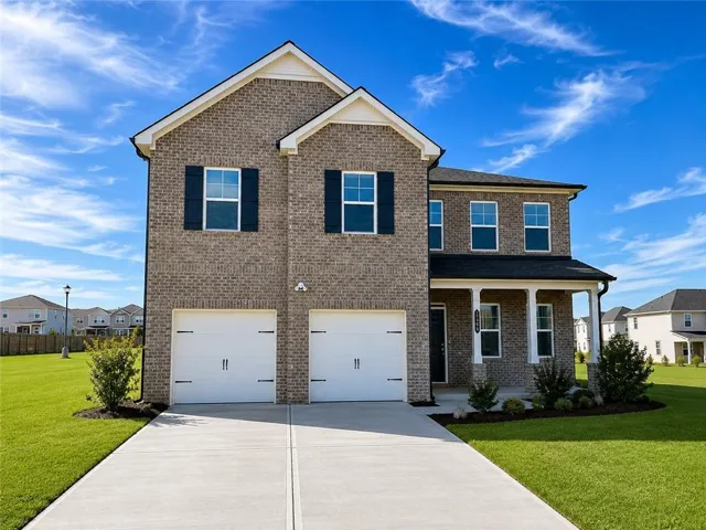 Two-story brick exterior featuring a covered front porch with white columns, a two-car garage, and a concrete driveway