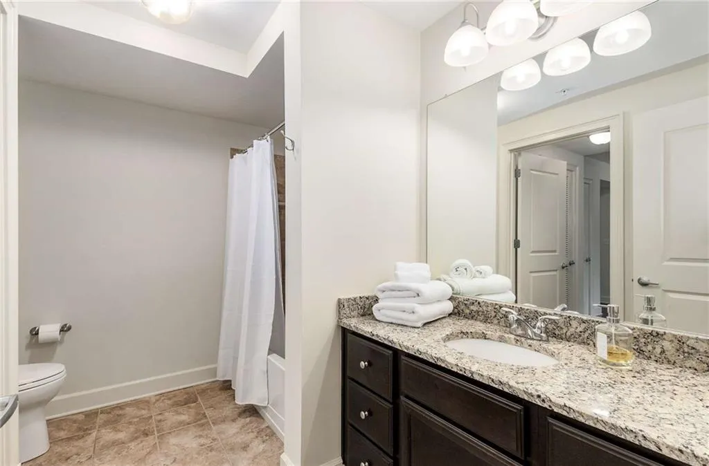 Bathroom featuring baseboards, vanity, shower / bathtub combination with curtain, and toilet