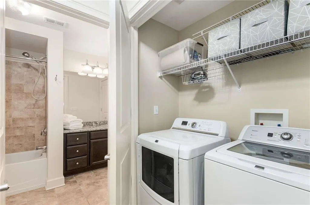 Laundry room featuring washing machine and clothes dryer, visible vents, and light tile patterned flooring