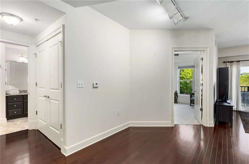 Hallway featuring baseboards, wood finished floors, and rail lighting