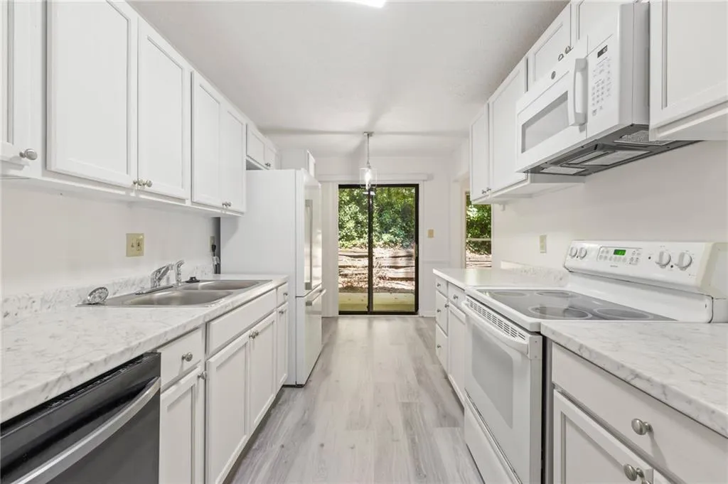 Kitchen featuring light hardwood / wood-style flooring, sink, light stone countertops, white cabinets, and white appliances Kitchen featuring light hardwood / wood-style flooring, sink, light stone countertops, white cabinets, and white appliances