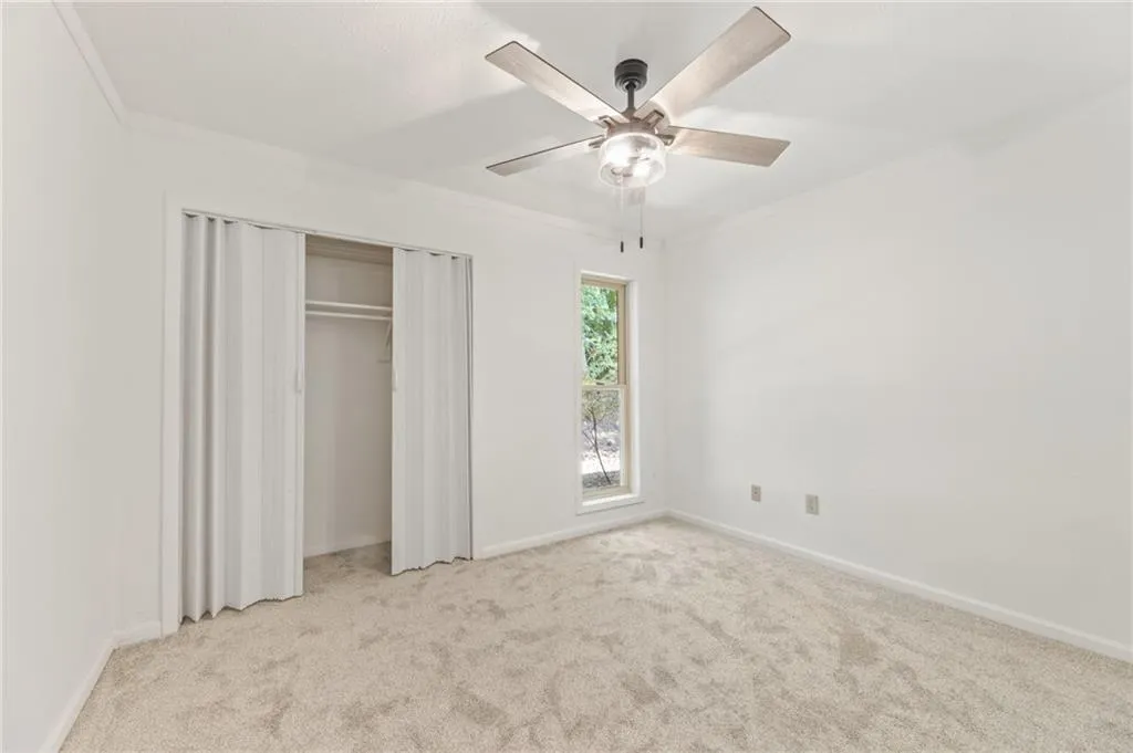 Unfurnished bedroom featuring ceiling fan, ornamental molding, and light colored carpet Unfurnished bedroom featuring ceiling fan, ornamental molding, and light colored carpet