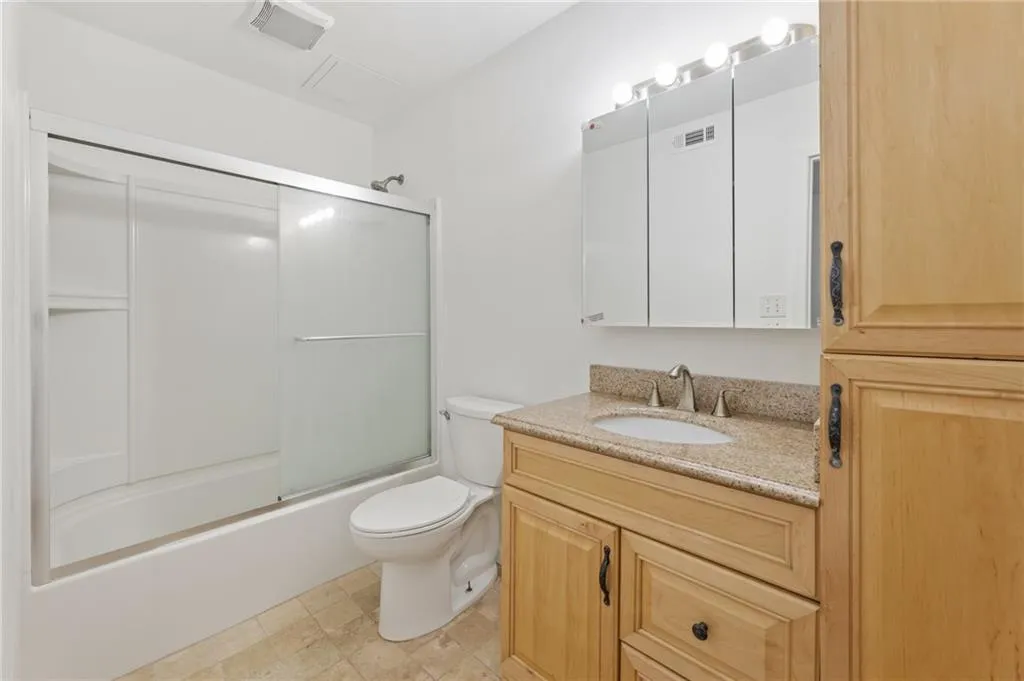 Full bathroom with combined bath / shower with glass door, toilet, tile patterned flooring, and vanity Full bathroom with combined bath / shower with glass door, toilet, tile patterned flooring, and vanity