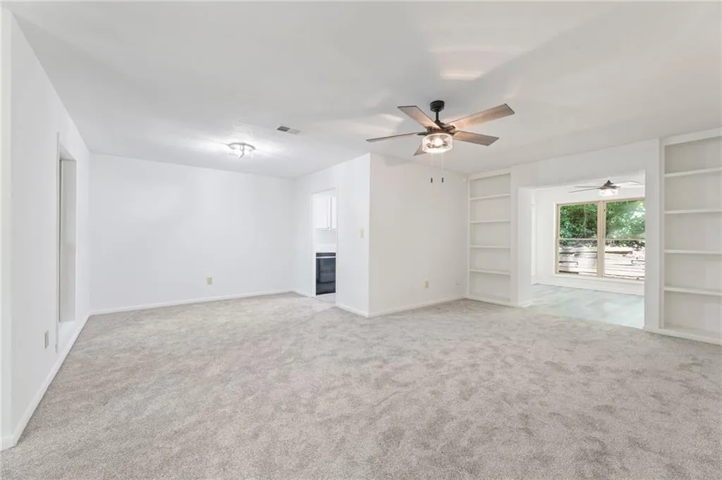 Unfurnished living room with ceiling fan and light carpet Unfurnished living room with ceiling fan and light carpet