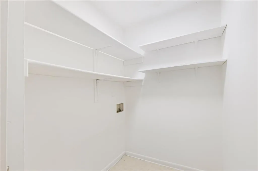 Clothes washing area with light tile patterned flooring and hookup for a washing machine Clothes washing area with light tile patterned flooring and hookup for a washing machine