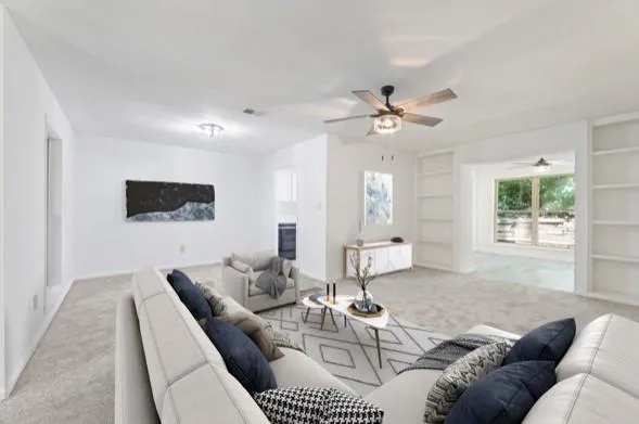 Carpeted living room with ceiling fan and built in features Carpeted living room with ceiling fan and built in features