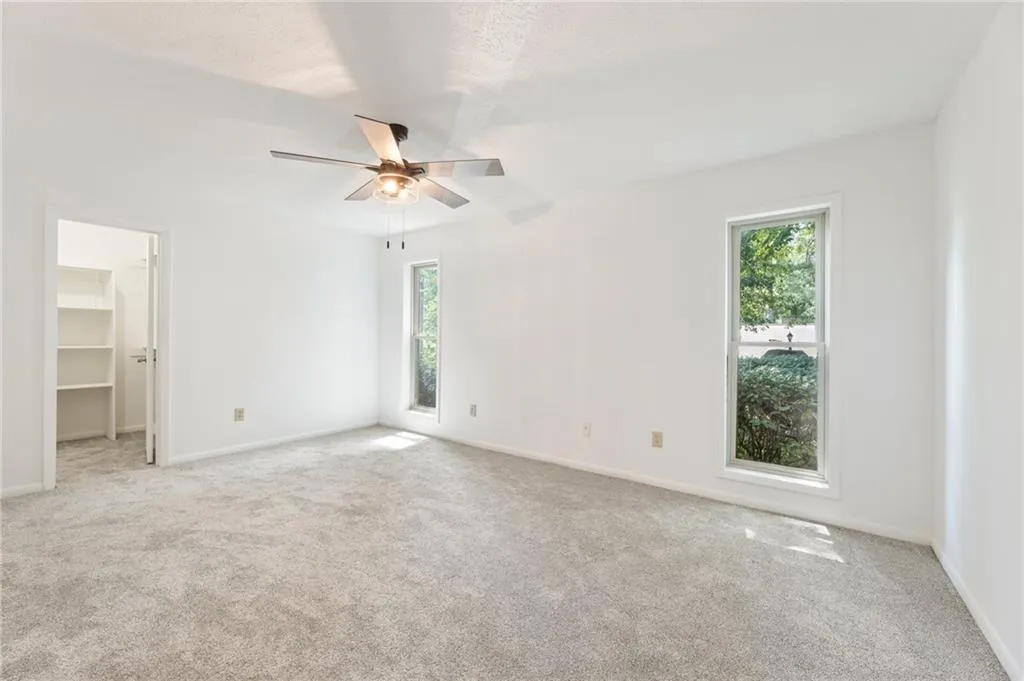 Unfurnished bedroom with ceiling fan, a closet, a spacious closet, and light colored carpet Unfurnished bedroom with ceiling fan, a closet, a spacious closet, and light colored carpet