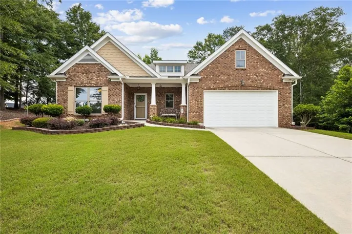 Brick exterior with complementary siding accents, a two-car garage, a concrete driveway, and established landscaping