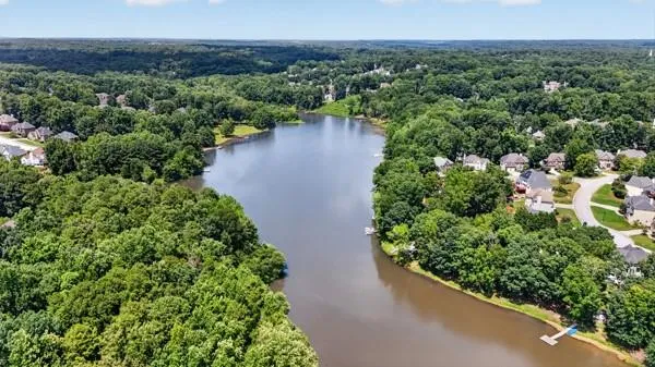 Expansive lakefront property featuring mature tree coverage, a private dock, and surrounding residential neighborhoods