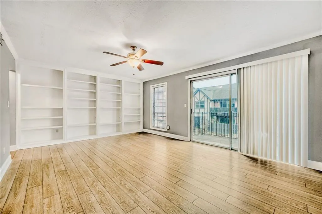 Empty room with ceiling fan, light wood-style floors, built in features, and ornamental molding