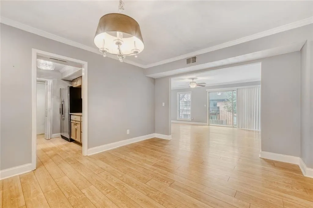 Unfurnished room featuring a chandelier, light wood-style floors, crown molding, and a ceiling fan