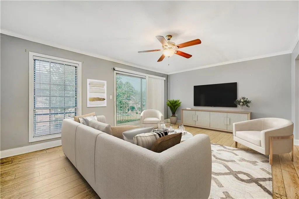 Living area featuring light wood finished floors, ornamental molding, and ceiling fan