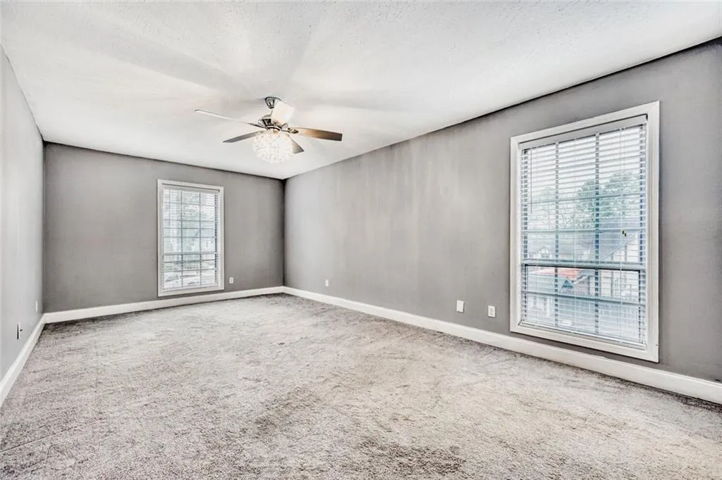 Spare room featuring light carpet, a ceiling fan, and a textured ceiling