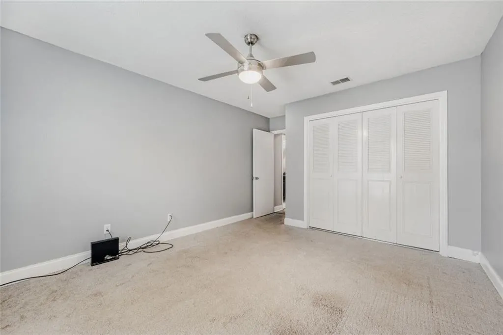 Unfurnished bedroom with light carpet, a closet, and ceiling fan