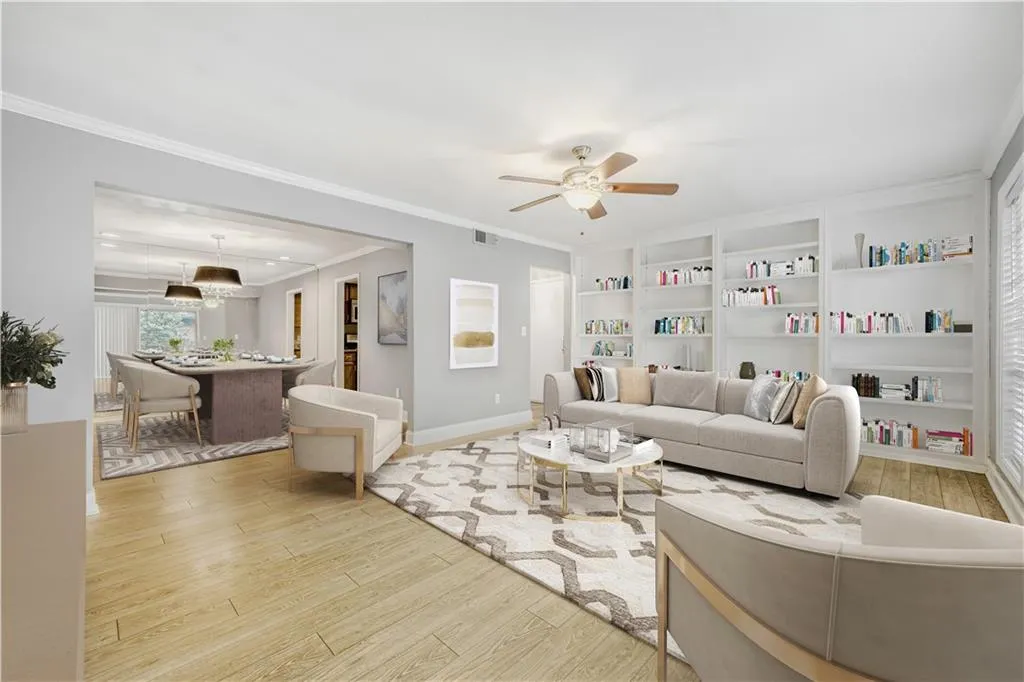 Living area featuring light wood-type flooring, a ceiling fan, built in shelves, and ornamental molding