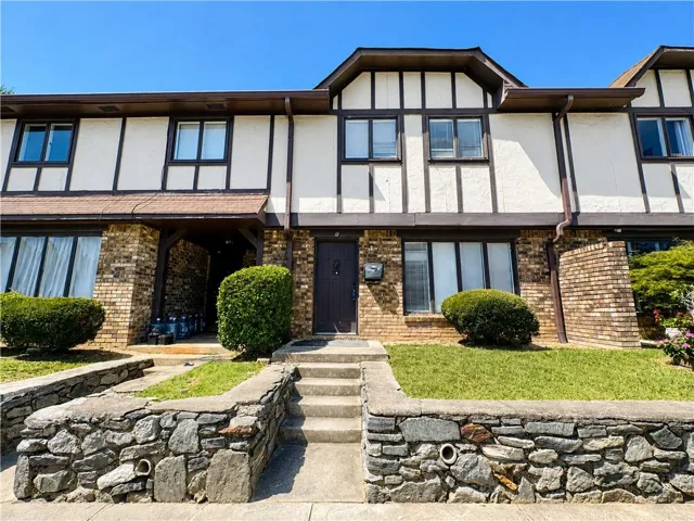 Two-story exterior with a mixed material facade featuring brick and stucco, stone retaining wall, and front entry stairs
