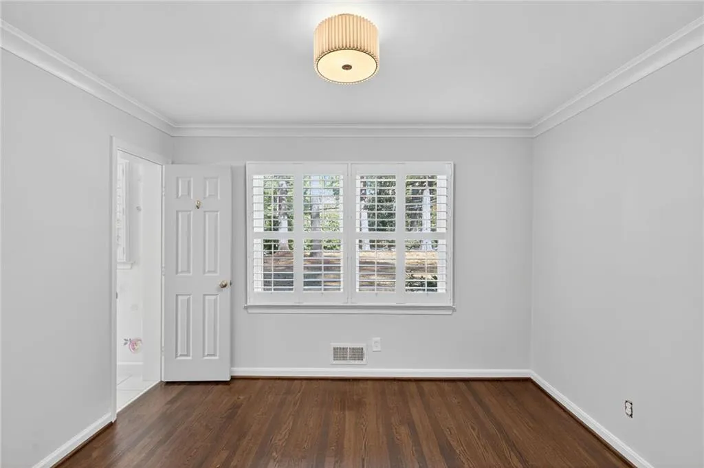 Unfurnished room with dark wood-type flooring and crown molding