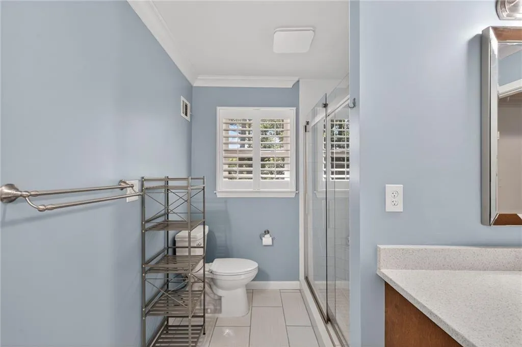 Full bathroom featuring vanity, a stall shower, ornamental molding, and light tile patterned flooring