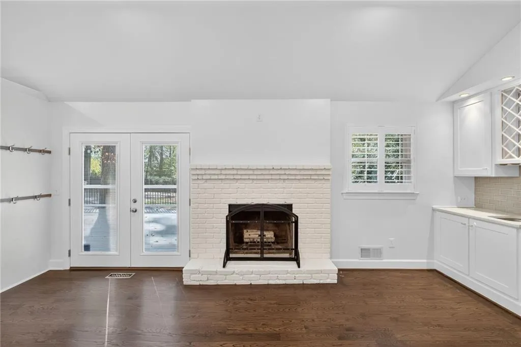 Unfurnished living room with vaulted ceiling, dark wood-style flooring, a fireplace, and french doors