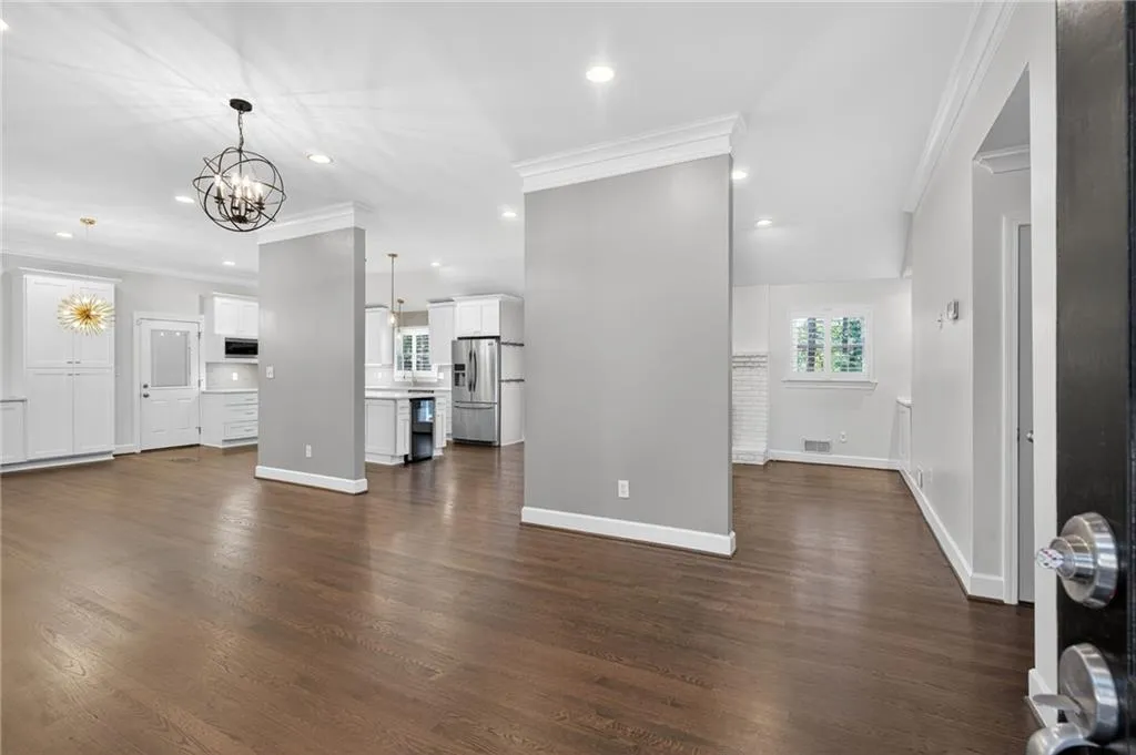 Unfurnished living room featuring crown molding, dark wood-style flooring, recessed lighting, plenty of natural light, and a chandelier