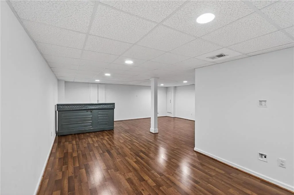 Finished below grade area featuring dark wood-type flooring, recessed lighting, and a drop ceiling